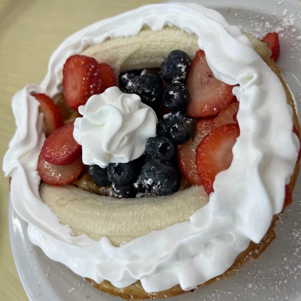 A waffle topped with sliced bananas, blueberries, strawberries, and whipped cream from Lighthouse Cafe.
