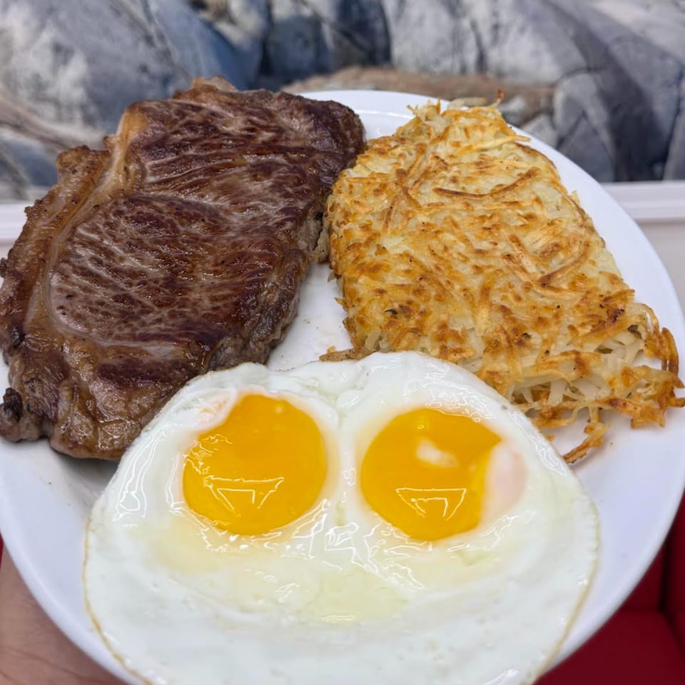 A breakfast plate with a steak, hash browns, and two sunny-side-up eggs.