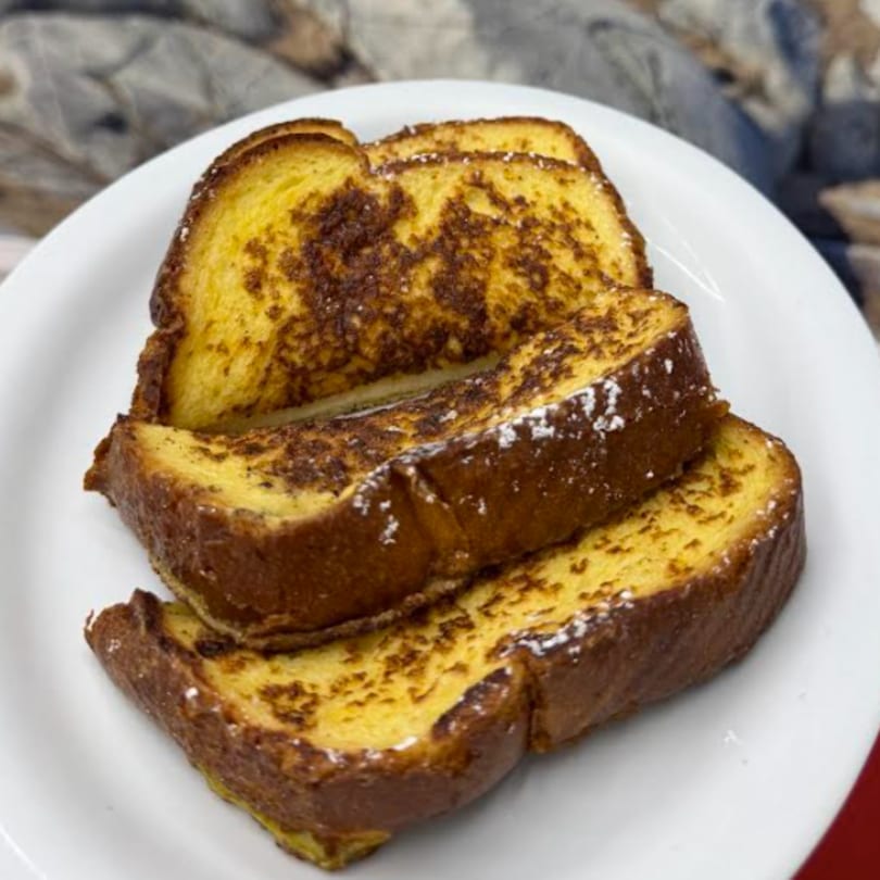 Three slices of golden-brown French toast, dusted with powdered sugar, on a white plate.